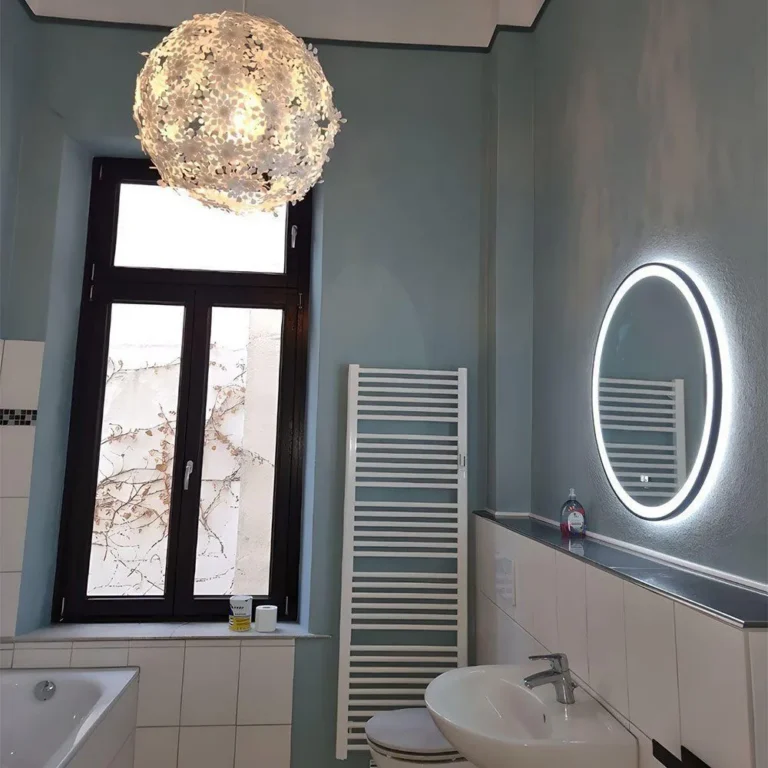 Badezimmer im Altbremer Haus mit hellblauen Wänden, weißer hoher Decke, rundem Leuchtspiegel und Kronleuchter