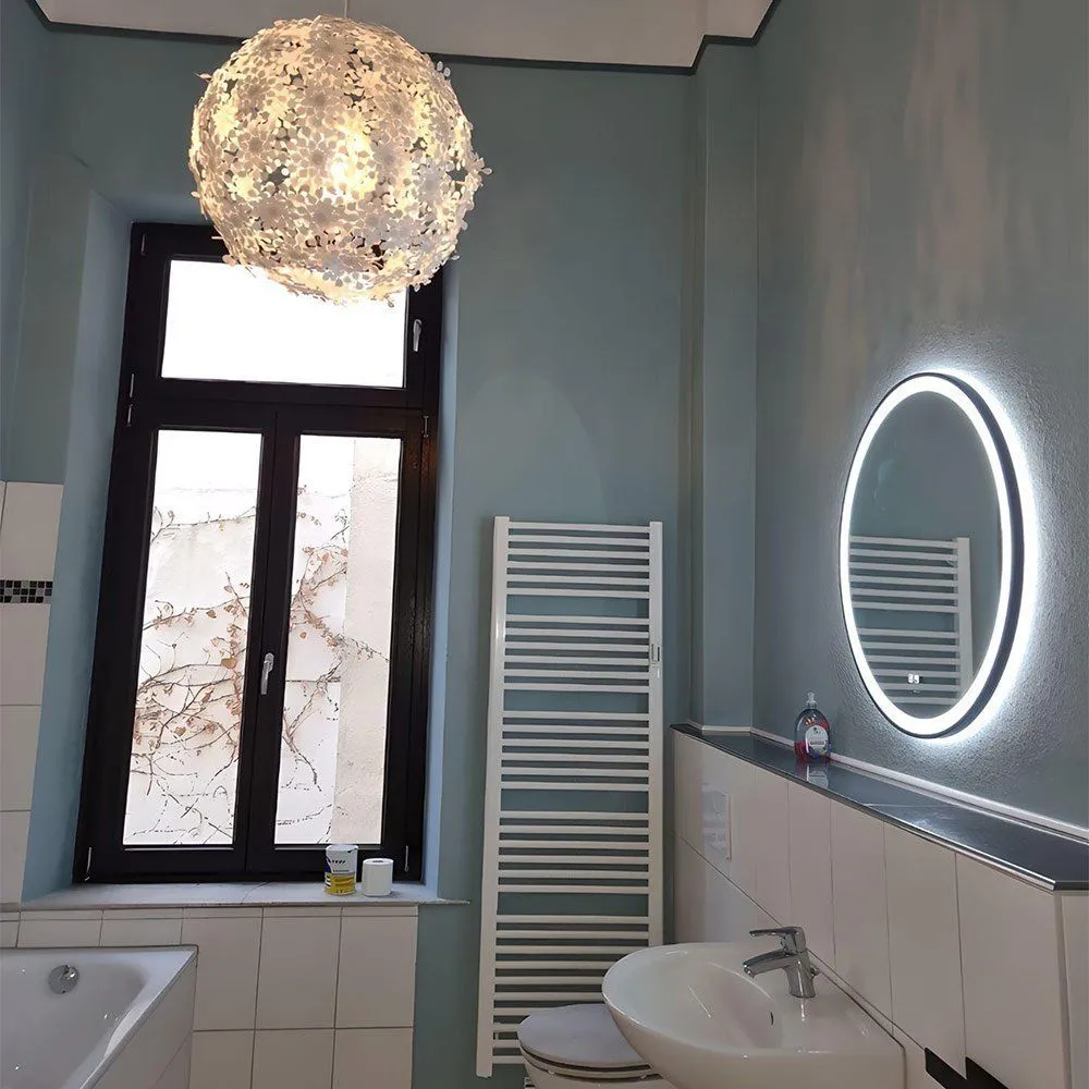 Badezimmer im Altbremer Haus mit hellblauen Wänden, weißer hoher Decke, rundem Leuchtspiegel und Kronleuchter
