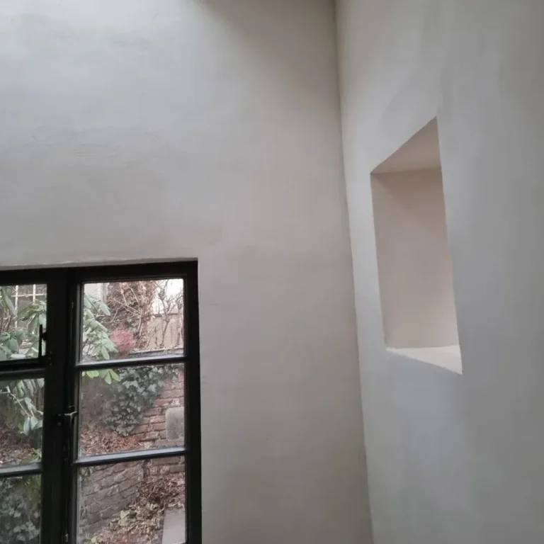 Kleinstes Haus Deutschlands: hell gestrichene Lehmputzwand mit Wandnische und Sprossenfenster