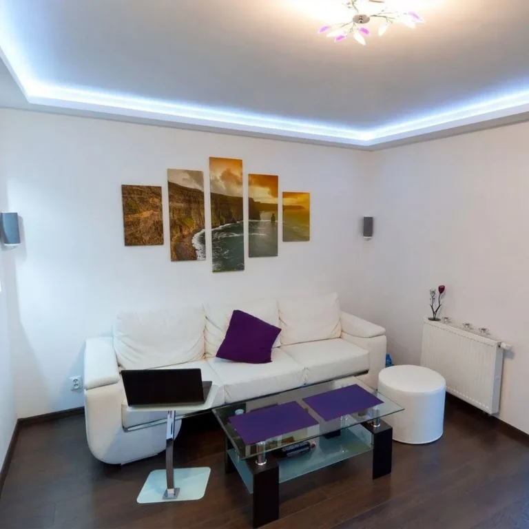 Wohnzimmer mit Lichtvoute und indirekter LED-Beleuchtung, Laminatboden und weißem Sofa