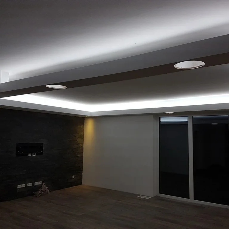 Wohnraum mit blau leuchtender Lichtvoute, dunkler Steinwand für den Fernseher und Vinylboden