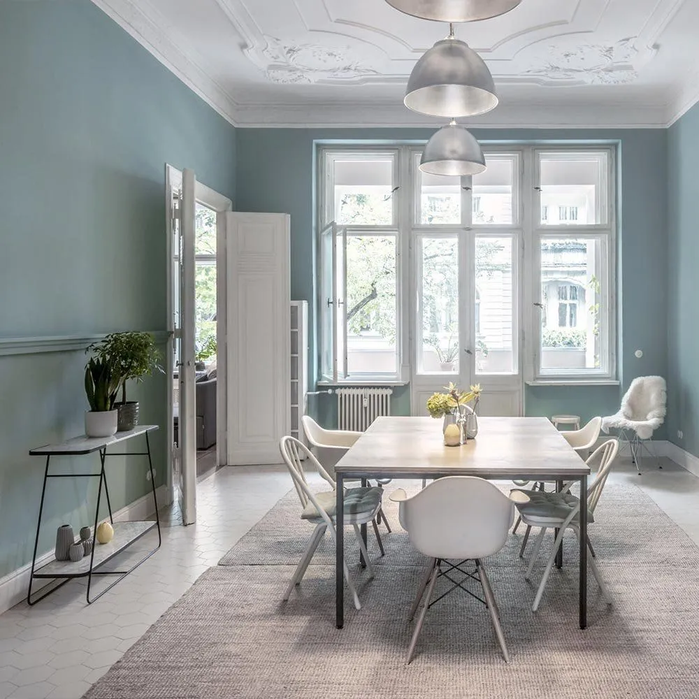 Esszimmer im denkmalgeschützten Altbremer Haus mit restauriertem Deckenstuck und blau gestrichenen Wänden
