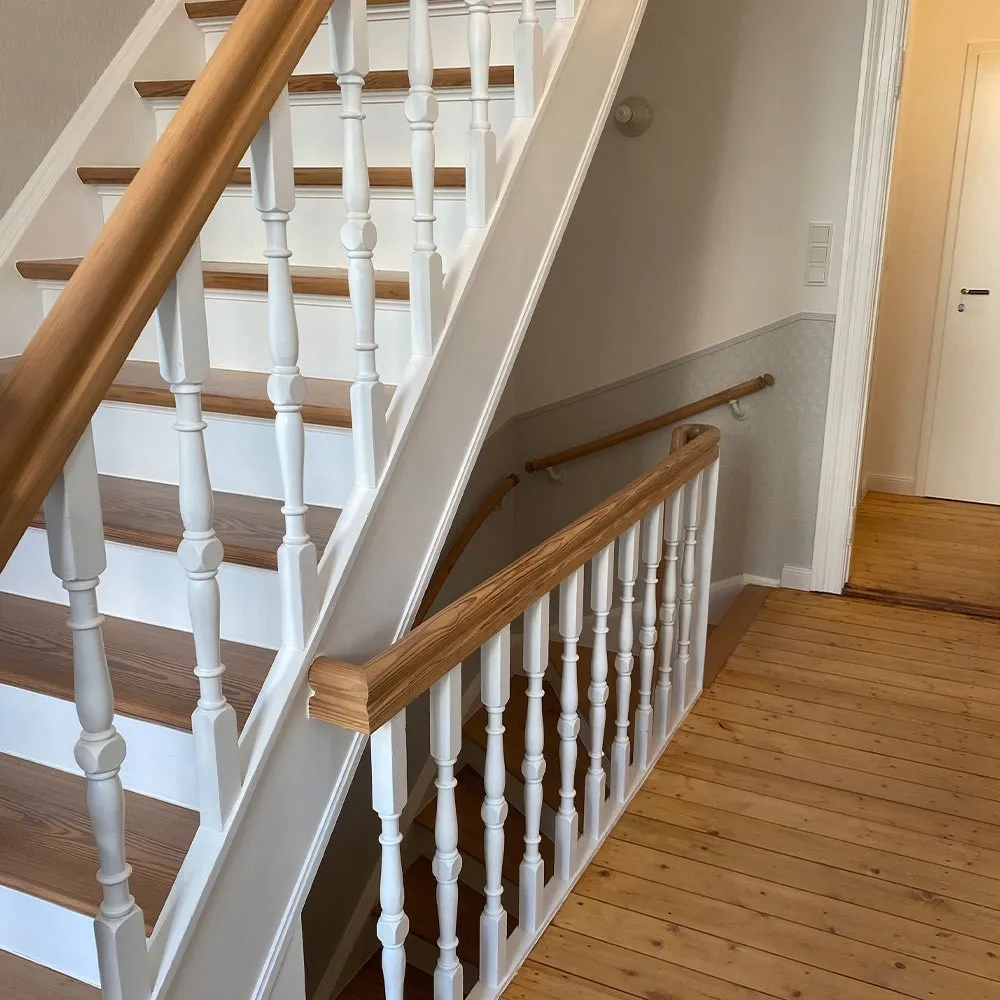 Treppengeländer vor der Sanierung mit dunklen Stufen, während der Arbeiten mit Palette gesichert