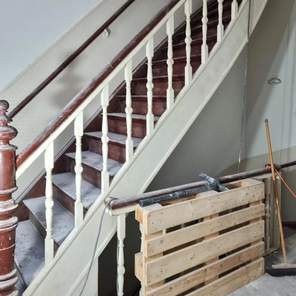 Sanierte gewendelte Treppe mit holzsichtigen Stufen, weißen Geländerstäben und Holzhandlauf