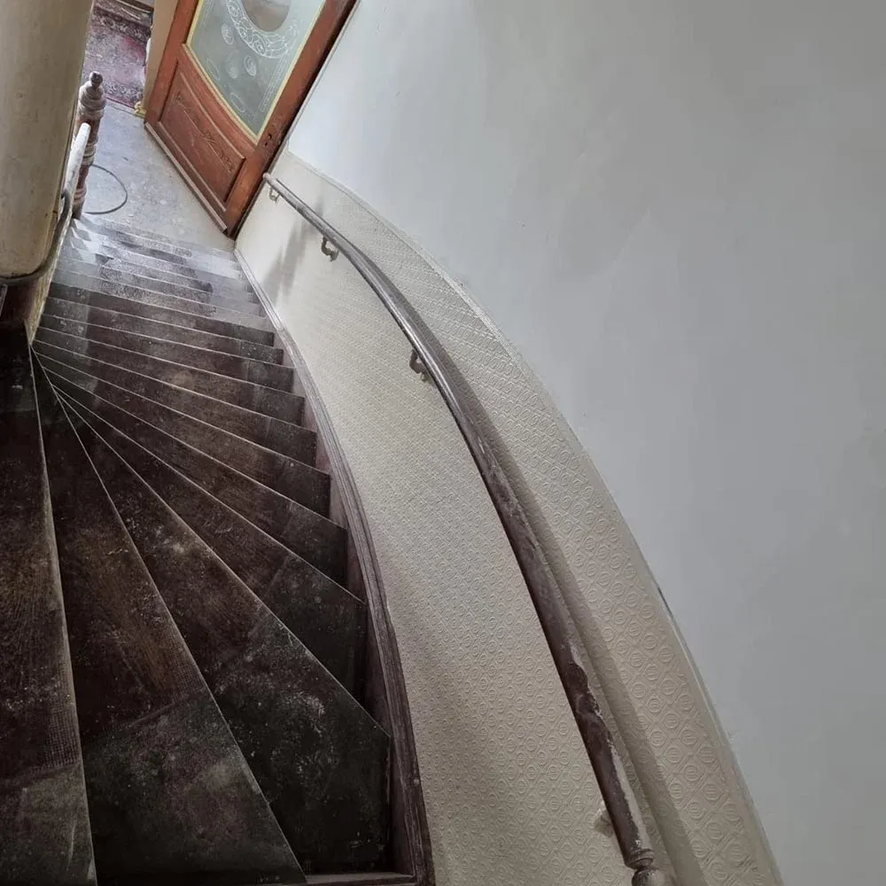 Sanierte Holztreppe mit holzsichtigen Trittstufen, weißen Setzstufen und restauriertem Antrittspfosten