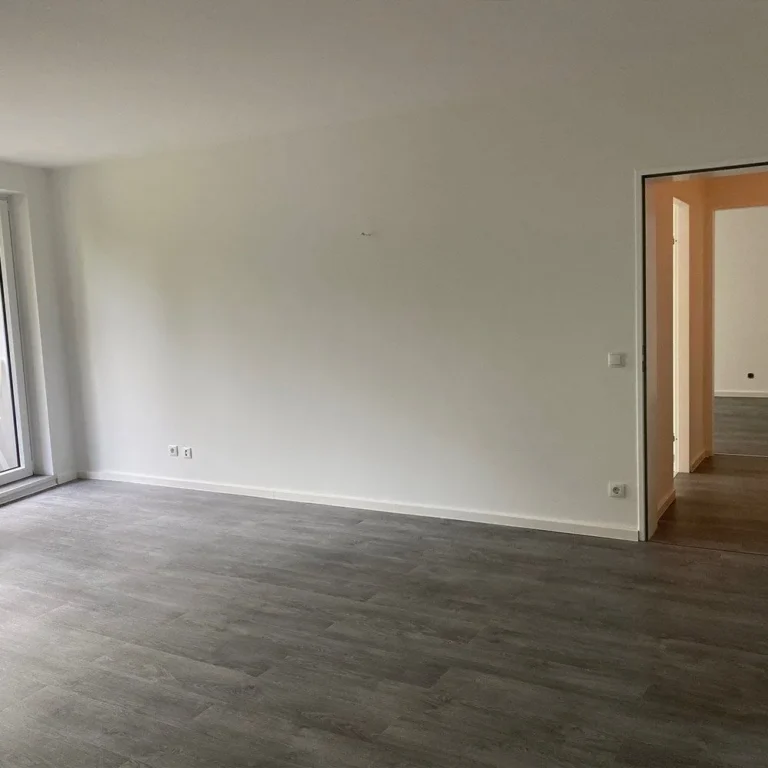 Leerer, renovierter Wohnraum mit grauem Rigid-Vinylboden und weiß gestrichenen Wänden